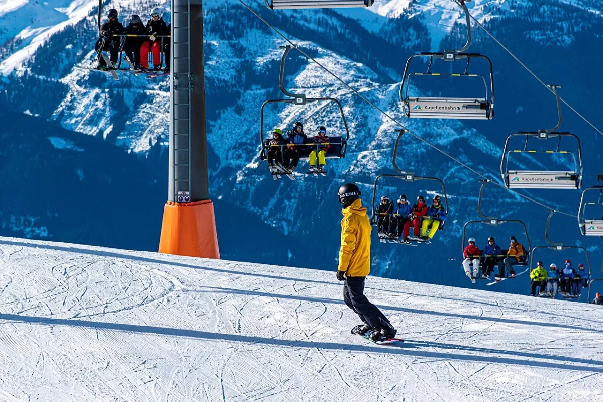 Snowboardzista zjeżdżający po zaśnieżonym stoku w słonecznym ośrodku narciarskim.